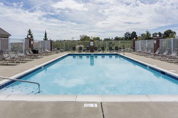 A large outdoor swimming pool surrounded by a metal fence.